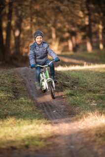 Six years old boy rides bicycle from the hill in the park