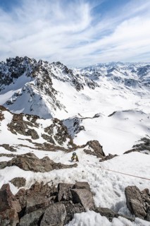 Mountaineer climbing up a steep snow slope, secured by a rope, ascent to the summit of Piz