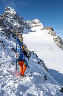 Mountaineer with skis at the fork Porta d'Es-cha, view of mountain peak Piz Kesch and glacier