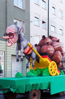 Chancellor candidate Friedrich Merz as a donkey figure in front of a cart with heavy sacks, debt