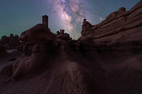 The night sky reveals the Milky Way over Goblin Valley's unique sandstone formations in Utah. The