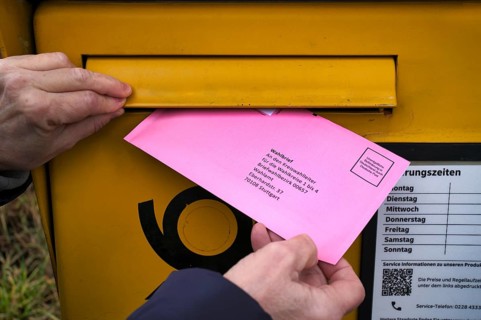 Woman throws ballot letter into mailbox, ballot envelope, bright red, pink, postal ballot, official