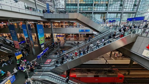 Large train station with escalators and lots of people in a busy atmosphere, Berlin central railway