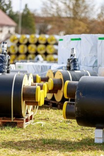 Stacked district heating pipes and district heating pipes with yellow ends lie in a pile in a
