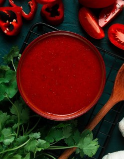 Tomato sauce, tomatoes and sweet pepper, Georgian Satsebeli sauce, with ingredients on a dark