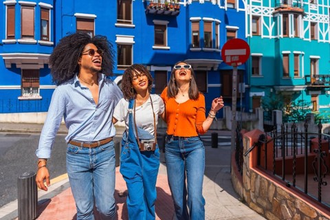 Three joyful friends walking together down a vibrant city street, soaking up the sights and sounds