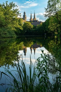 The towers of the monastery church of Marienmünster Abbey are reflected in a tranquil lake