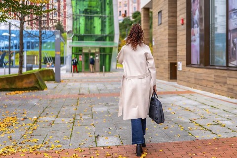 Rear view of an african american businesswoman walking to the office along a street with autumn