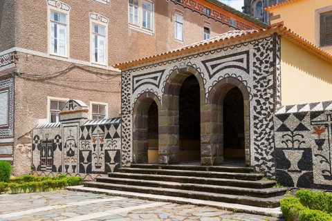 Ein historisches Gebäude mit kunstvoller Mosaikfassade und imposanten Bögen, in sonnigem Wetter