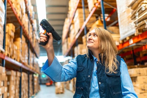 Woman worker scanning package with bar code reader in a distribution warehouse