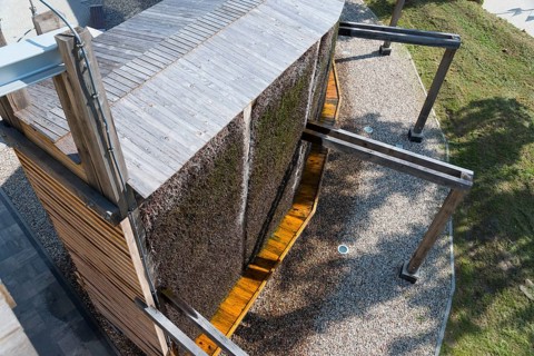 Modern wooden structure with gravel floor and shade, surrounded by vegetation, brine, graduation