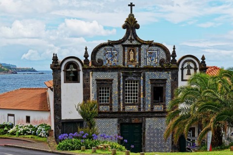 Historic church Convent of Caloura on the coast with blue and white tiles and sea view, surrounded