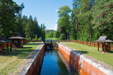 Canalised watercourse through the forest with lock and wooden railings in summer, Sluza Perkuc,