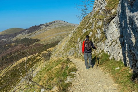A man walking towards the top of Mount Ernio or Hernio in Gipuzkoa at sunset, Basque Country