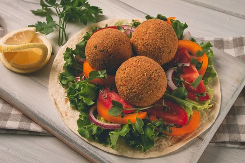 Tortillas, wrapped falafel balls, with fresh vegetables, vegetarian healthy food, on a wooden white