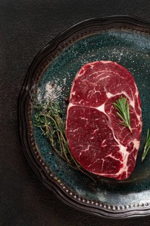 Steak made from fresh beef, with herbs and various spices, on a plate, ready to cook, there are no