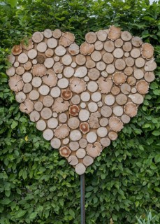 Wooden discs in the shape of a heart in front of dense green leaves, Münsterland, North
