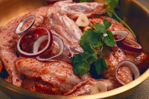 Chicken wings, in a brass saucepan, ready for cooking, grilling or baking, in a home kitchen, no