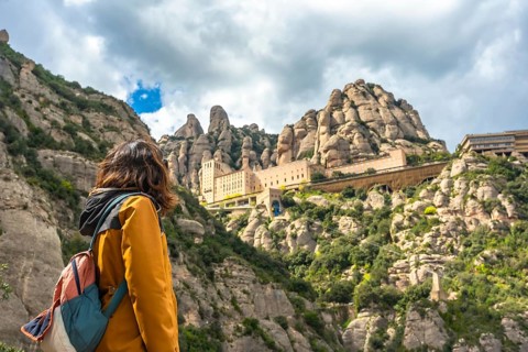 Hiker admiring santa maria de montserrat abbey, a benedictine monastery located on the mountain of