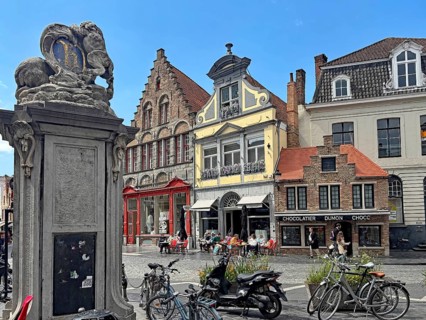 Lively square with cafés, bicycles and a decorative statue, Bruges, West Flanders, Belgium