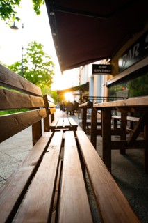 A sun-drenched evening in a street with wooden benches and an outdoor café, Berlin, Germany