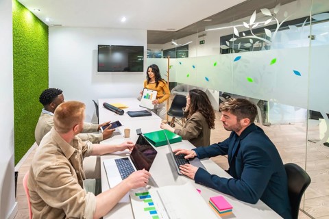 Marketing team working together in a modern office, using laptops and analyzing graphs during a