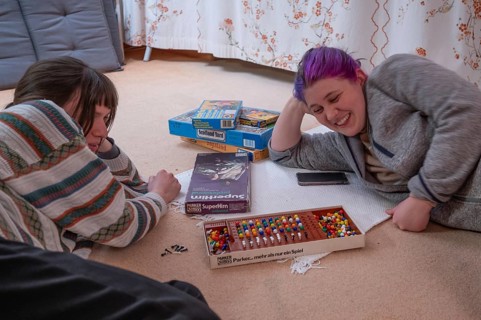 Two young woman playing a parlour game on the carpet in the living room, Bavaria, Germany