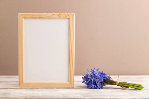 Wooden frame with spring snowdrop flowers bluebell on beige pastel background. side view, copy