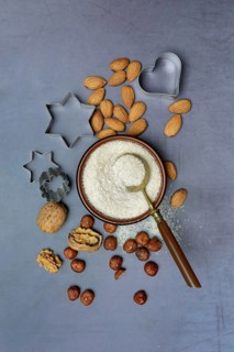 Grated coconut in a bowl and spoon, various nuts and cookie cutters
