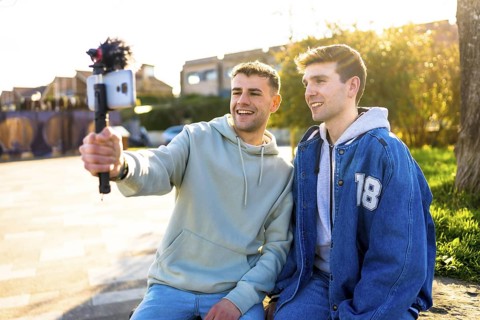 Two men creating content for their vlog channel, recording a video with a smartphone and external
