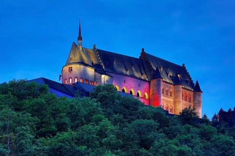 Vianden Castle, hilltop castle illuminated in the colours of the Luxembourg flag for the bank