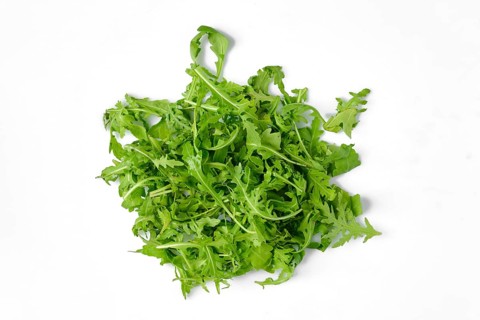 A pile of freshly harvested arugula on a clean white surface, highlighting its vibrant green color