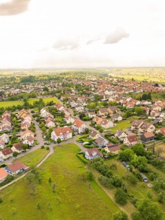 Densely built-up residential area with numerous houses and gardens, surrounded by green countryside