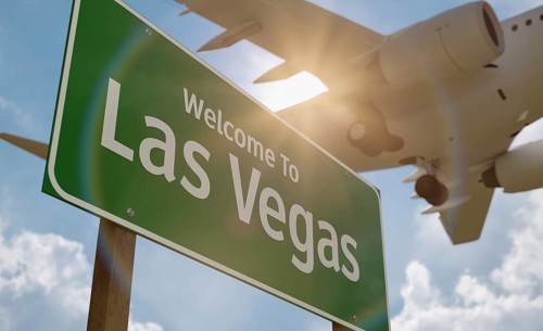 Welcome to las vegas green road sign with low flying airplane just above with landing gear down