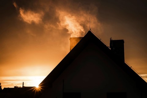 Smoke from the chimney of house during sunset