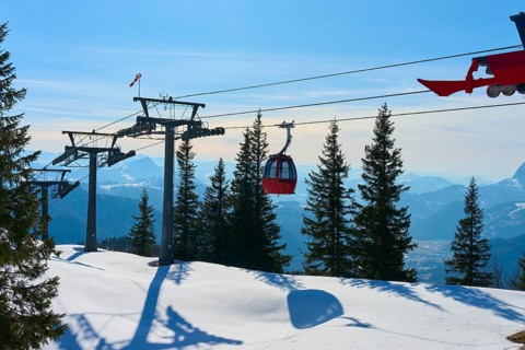 Cable car travelling through a snowy landscape with fir trees and mountain views, Steinplatte,