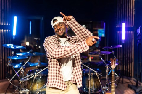 Young male music artist dancing urban style in professional recording studio with instruments in