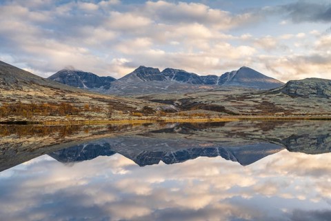 Reflection of the autumn landscape in Rondane National Park, mountains Høgronden, Midtronden and