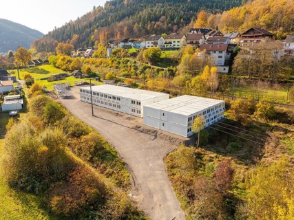 Container building in a natural environment with autumn trees and a village, refugee accommodation