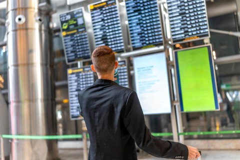 Businessman looking at timetable display while waiting for his flight, travel and business concept
