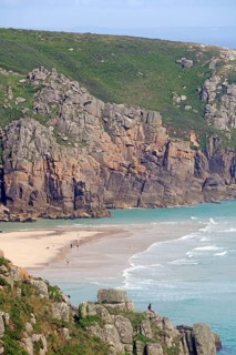 Kleiner Sandstrand eingebettet zwischen steilen Klippen und ruhigem Meer, Porthcurno, St Levan,