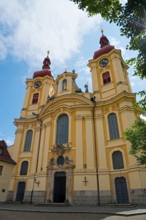 Detailed view of a baroque church with a yellow façade and red towers under a blue sky, pilgrimage