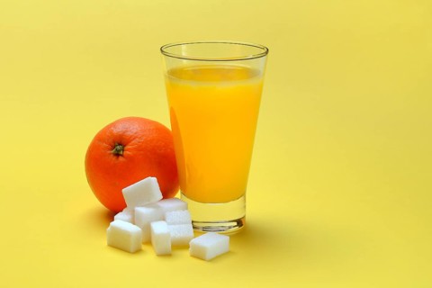 Orange juice in a drinking glass, half an orange and sugar cubes