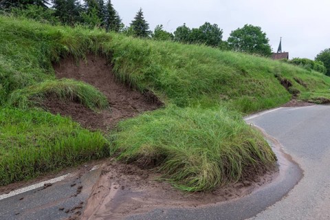 Symbolic image of climate change, slippery slope on a country road after heavy rainfall, near