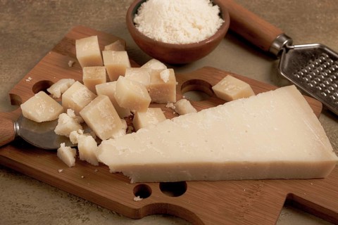 Freshly sliced and grated cheese, parmesan cheese, Gran gusto. Grana padano. on a wooden chopping