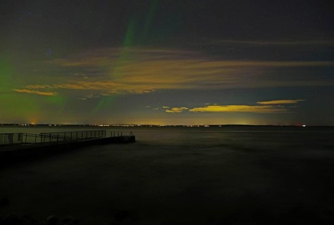 Dark night sky with northern lights and scattered clouds, sea in the foreground, beach, Tönsberg,