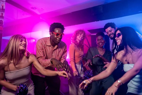 Group of multi ethnic friends enjoying a night out at the disco, dancing and having fun together