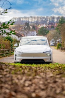 Electric car on quiet country road, surrounded by nature and clouds in autumn landscape, Tesla, New