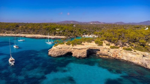 Breathtaking aerial view capturing sailboats gliding through the crystal clear turquoise waters of
