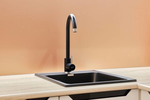 A modern kitchen sink is showcased with a sleek, high-arch faucet featuring a single handle. The